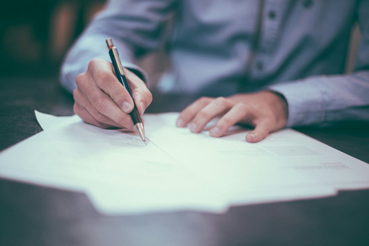 Person reviewing and signing documents at a desk