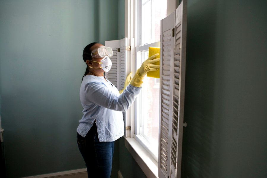 Cleaner in gloves wiping a window frame